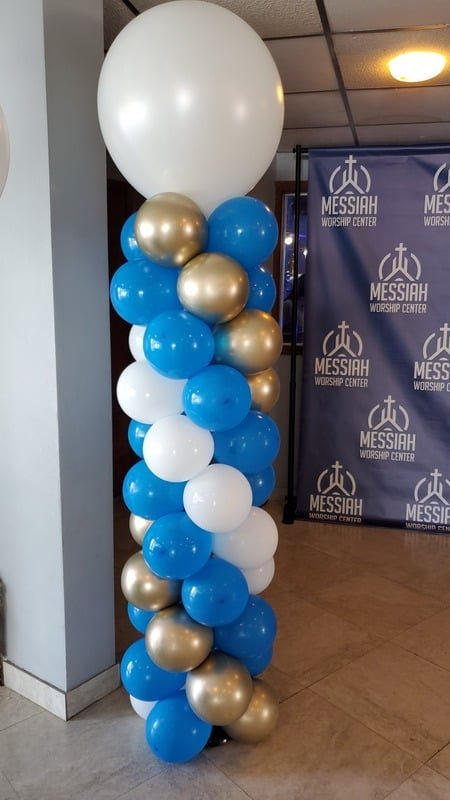 Blue, gold and white balloon column topped with a large white balloon