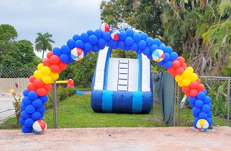 Primary-colour welcoming balloon arch with beach balls in front of a water slide